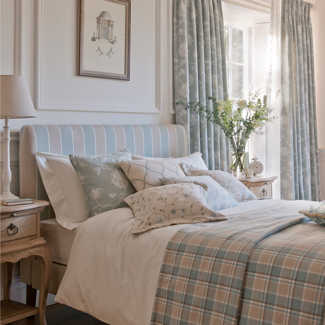 country cottage style bedroom with a thick quilt and curtains